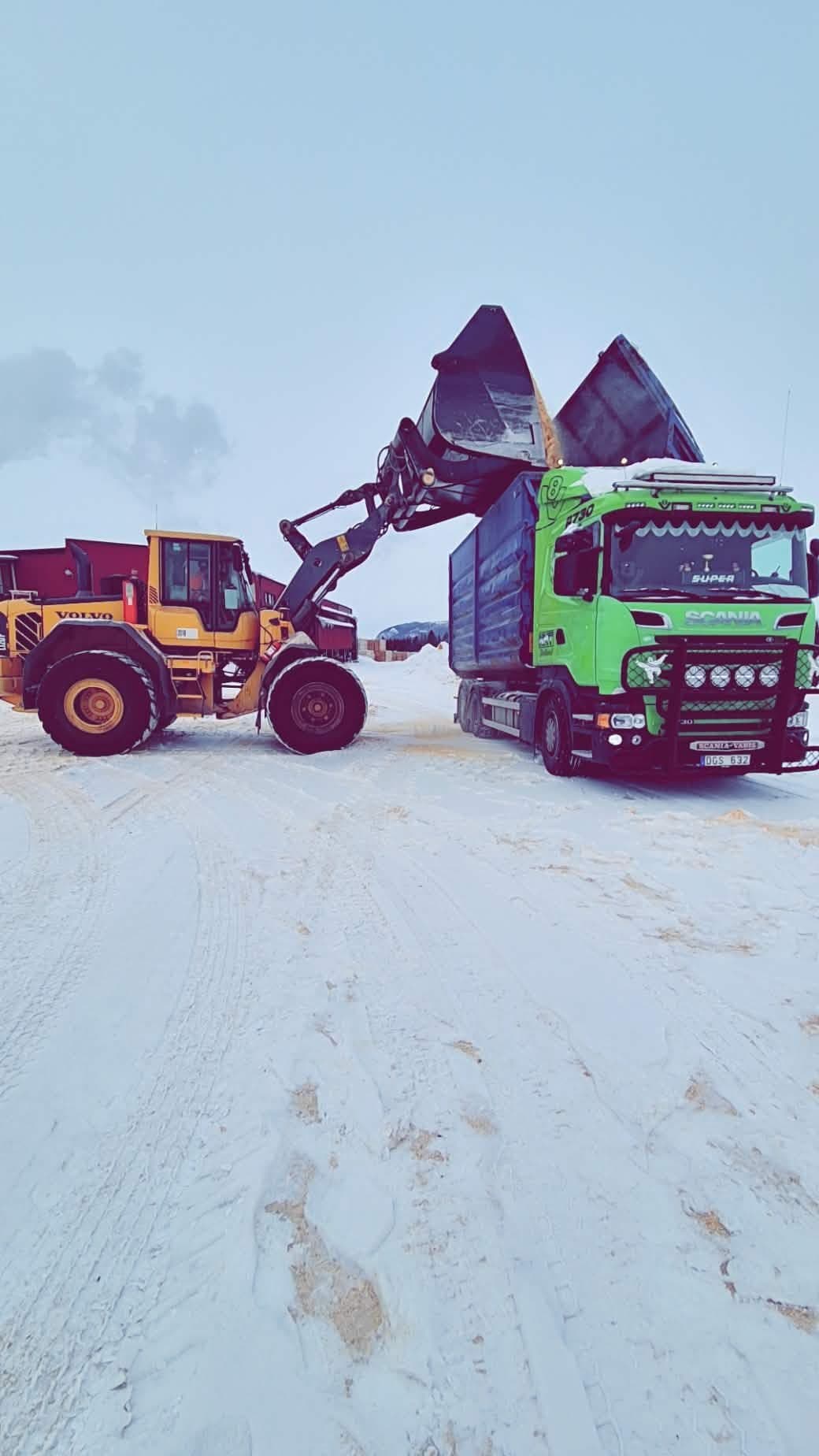 En hjullastare tömmer skopan i containern på Scanian, på en snötäckt plan