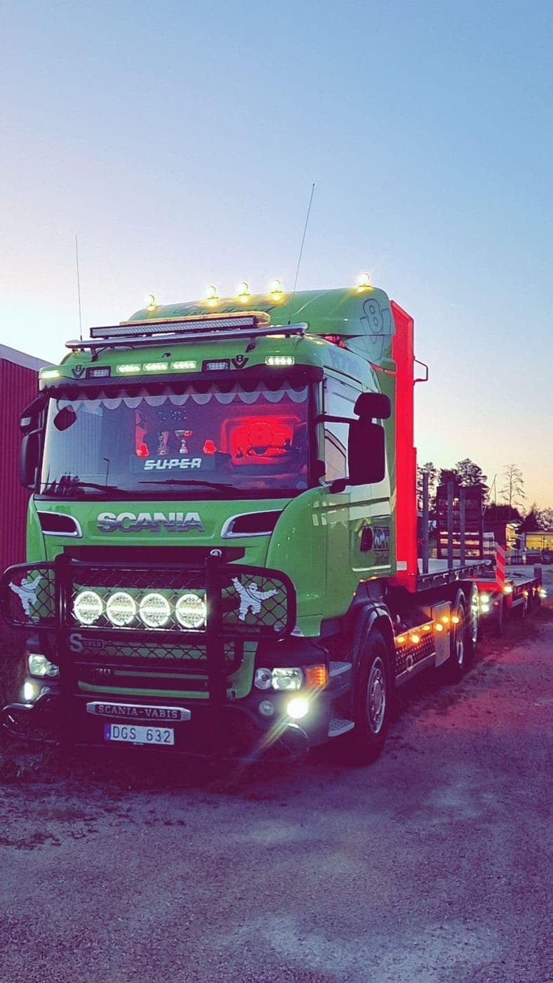 Scania i skymningen med extraljusen tända