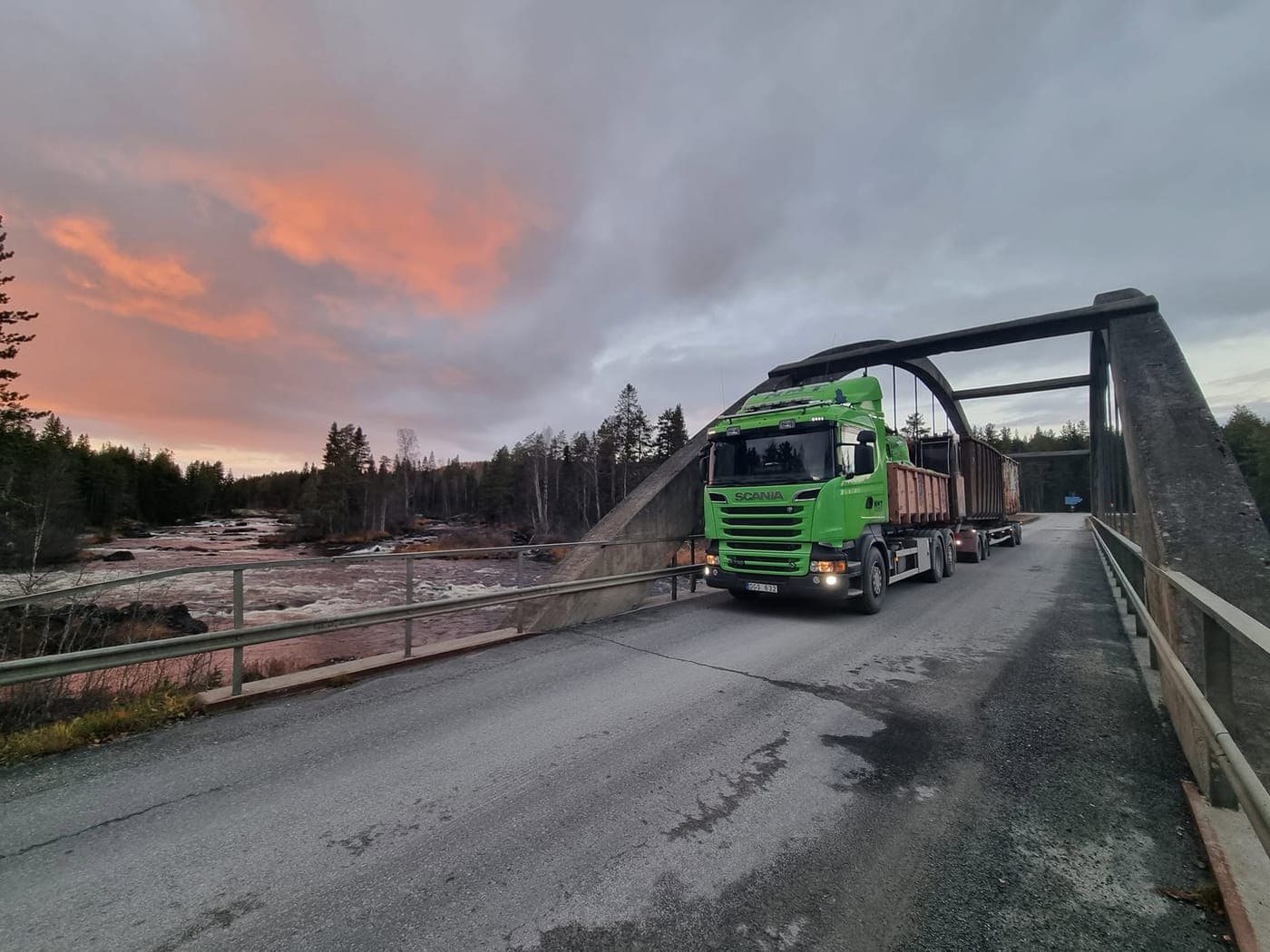 Lastbil kör över en bro i solnedgången