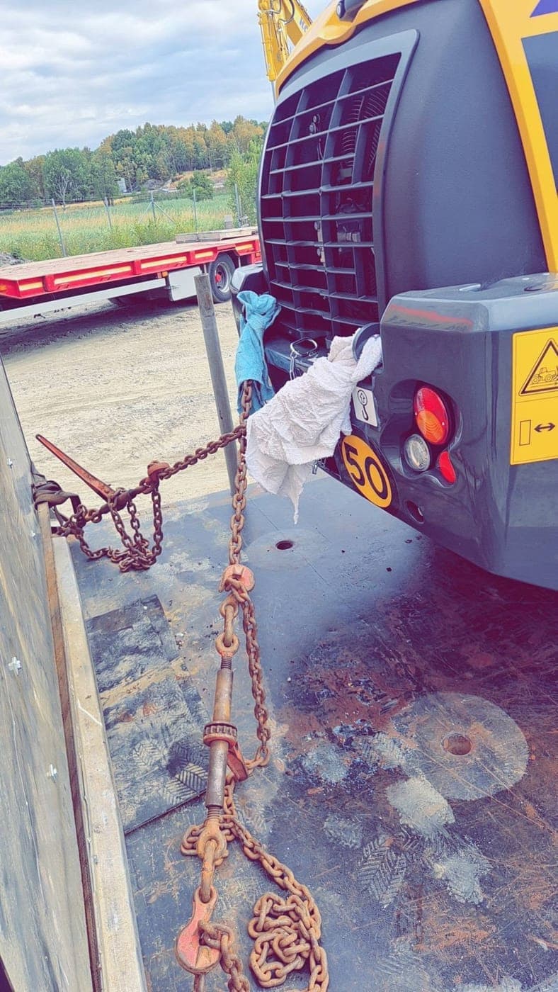 Kättingar spända runt en hjullastare på flaket