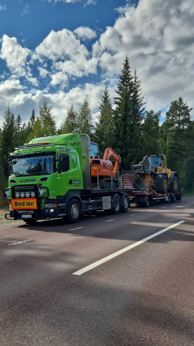 Lastbil med grävmaskin och hjullastare längs vägen