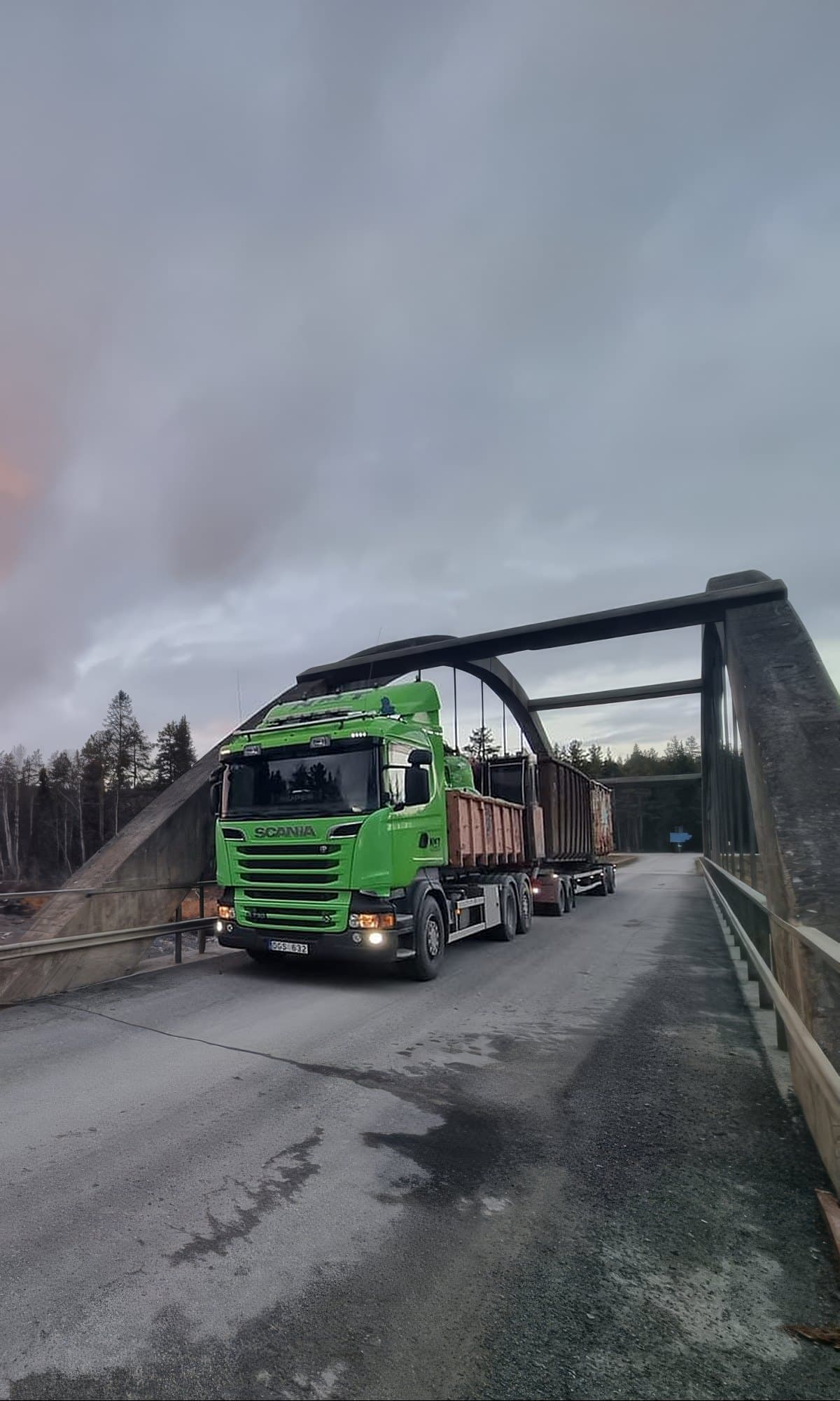 NMT Jämtlands limegröna Scania kör över en bro vid forsen i solnedgången