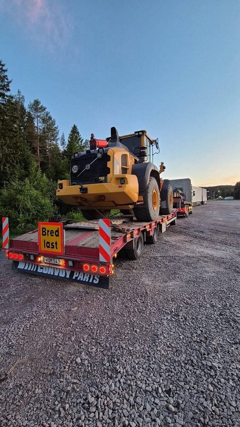 Hjullastare på maskinsläpet med skylt Bred last